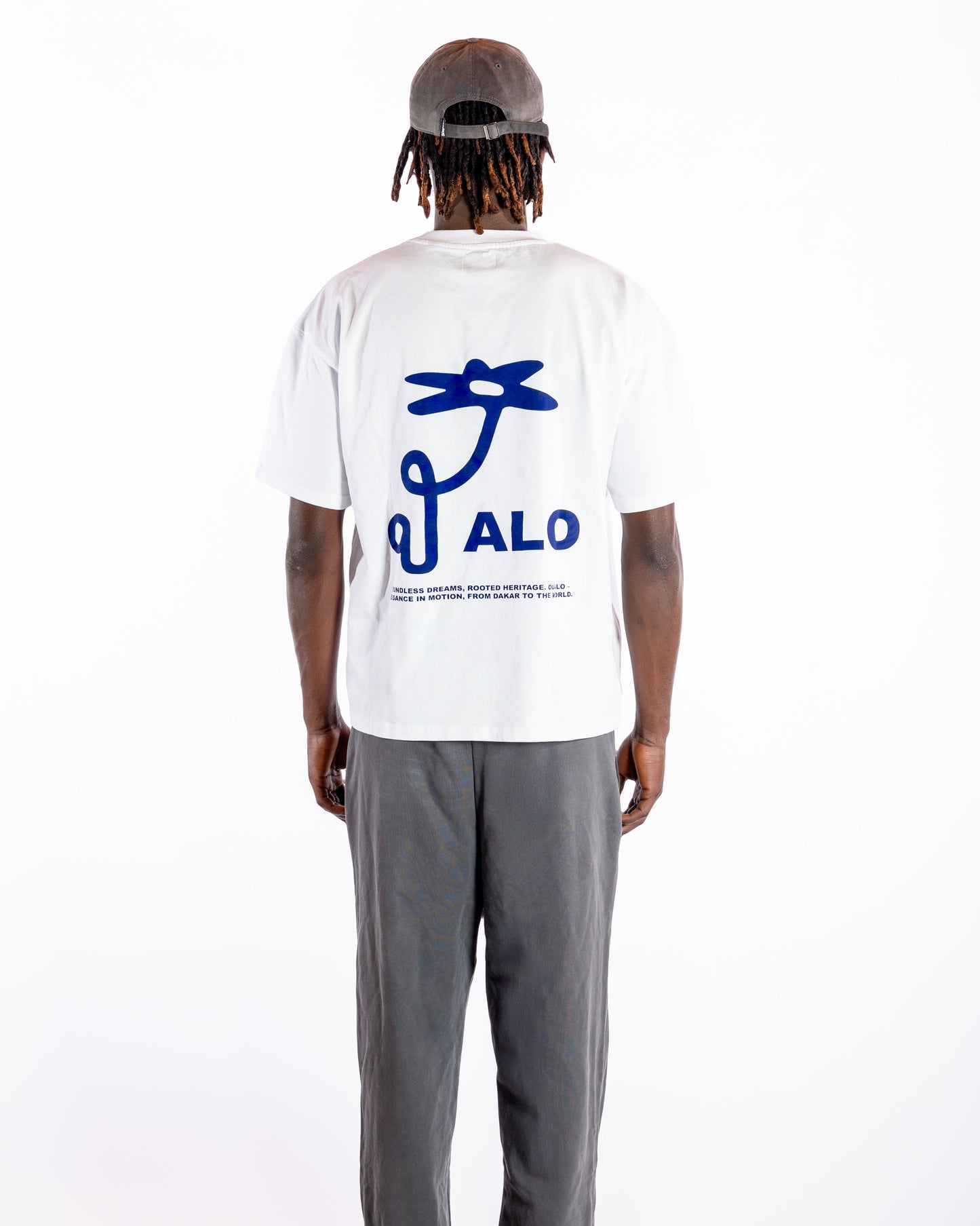 Person wearing a white t-shirt with blue graphic and 'OUALO' text on the back, standing against a white background.