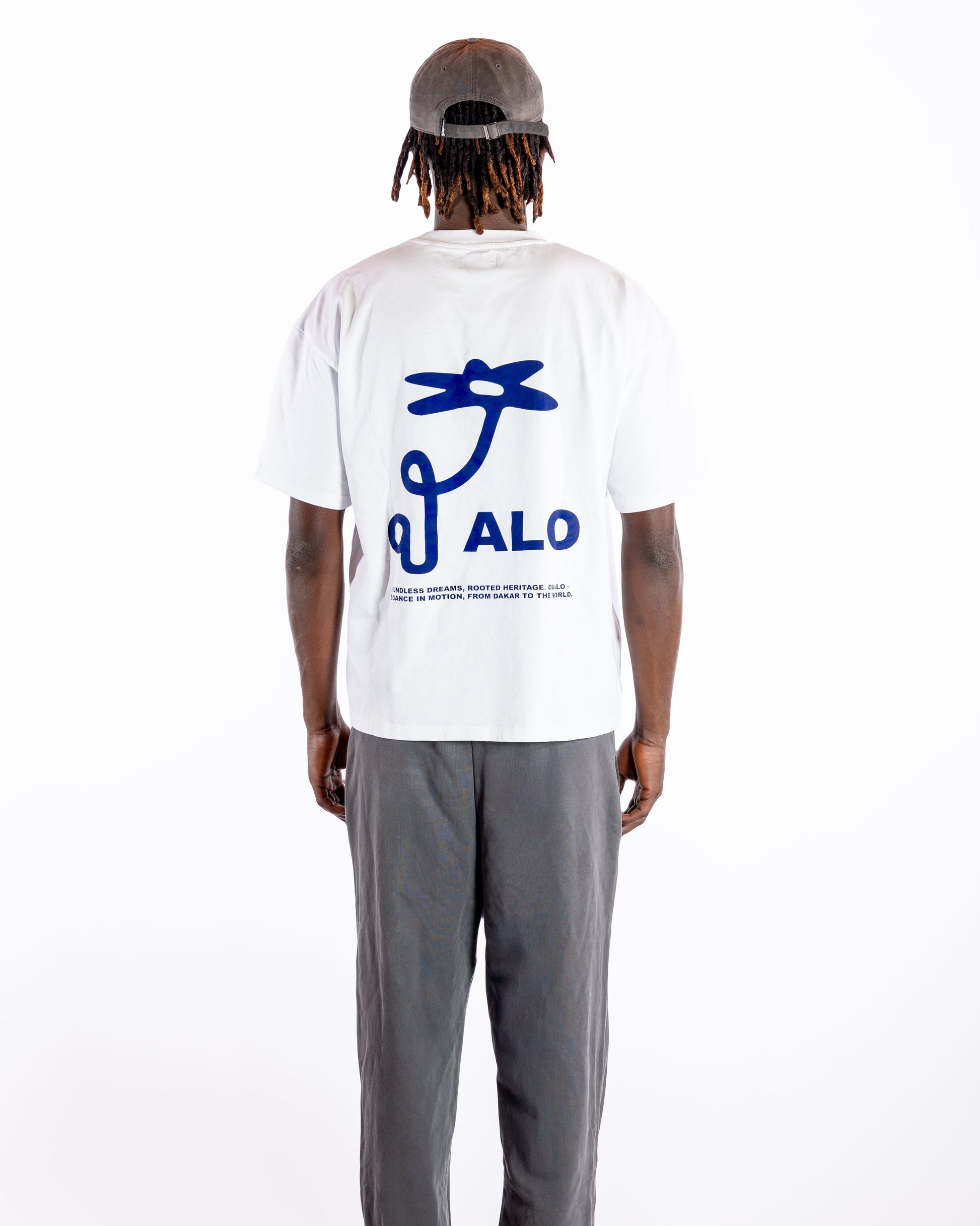 Person wearing a white t-shirt with blue graphic and 'OUALO' text on the back, standing against a white background.